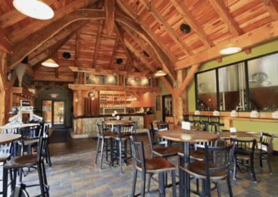 A spacious restaurant featuring wooden beams and several tables arranged for gatherings or meetings